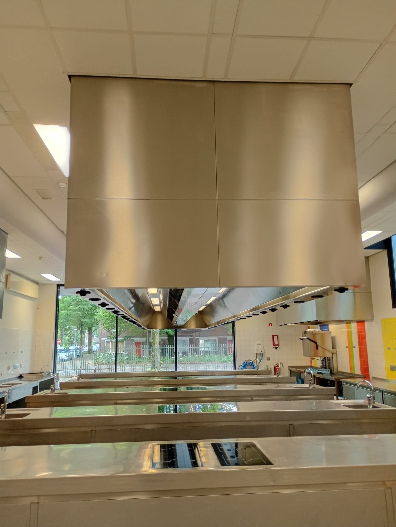 Grootkeuken met schone RVS afzuigkap boven de kookeilanden