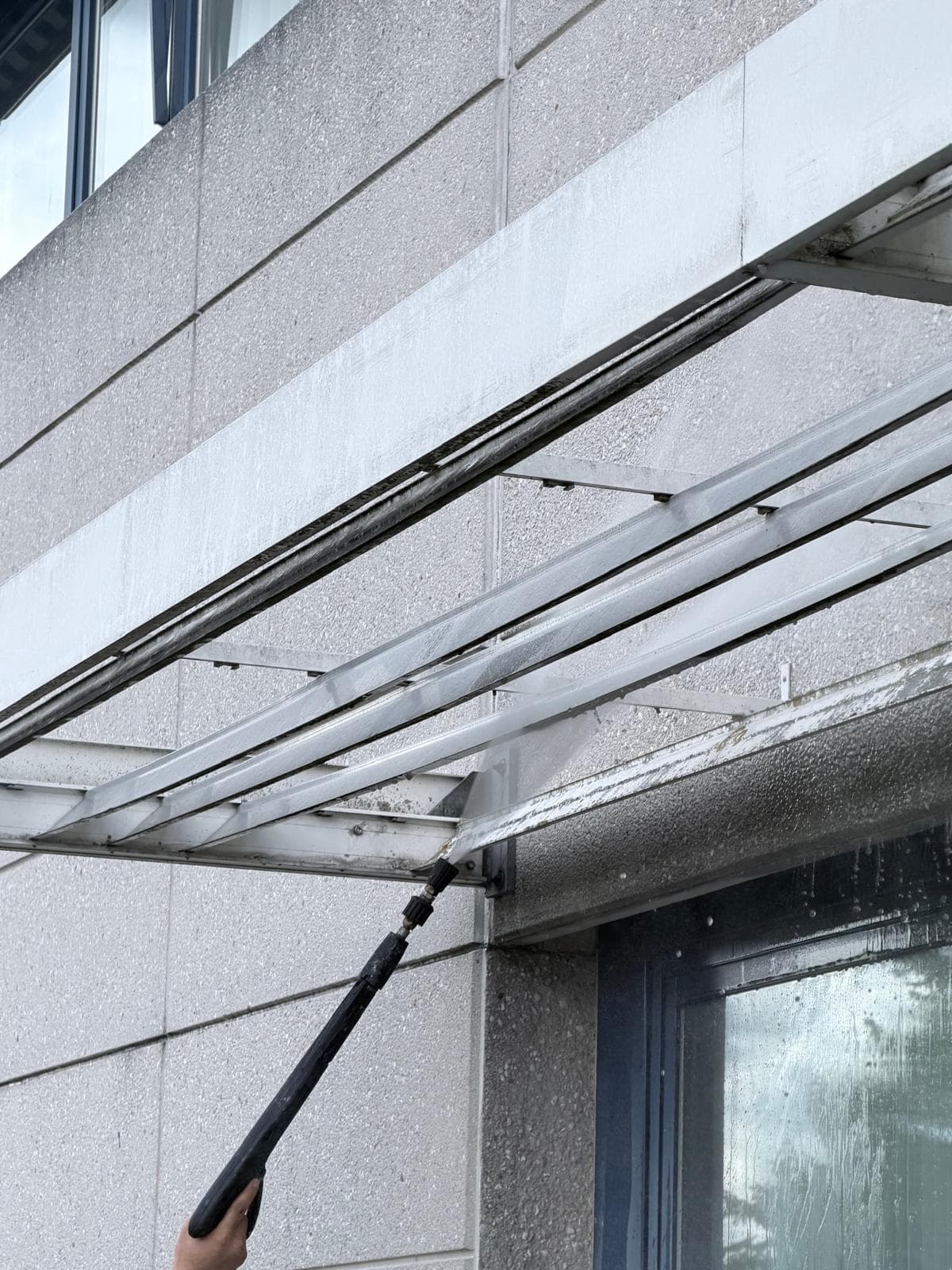 Luifel en gevel tijdens hogedrukreiniging met telescooplans